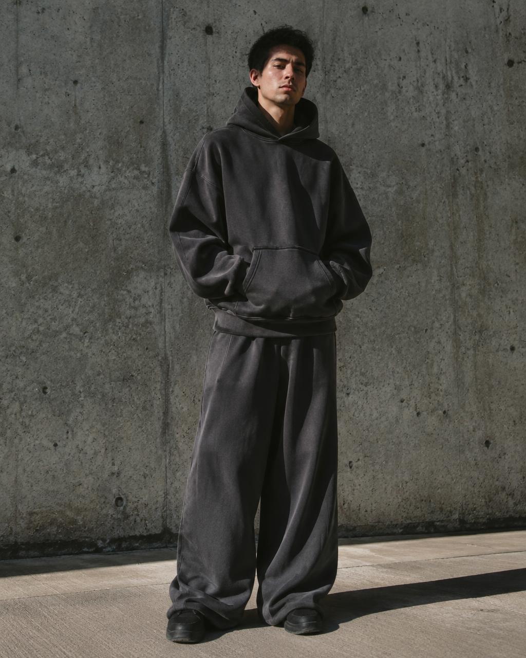Streetwear campaign — black hooded coat against concrete architecture